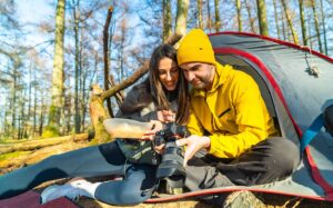 camping für anfänger tipps - Paar beim Camping im Zelt – Frühstück & gemeinsame Erinnerungen festhalten