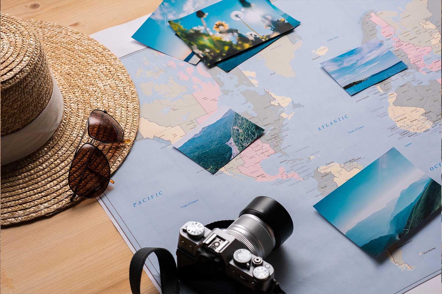 Symbolbild für Reiseplanung mit Kamera, Weltkarte und Urlaubsfotos – Reisekrankenversicherung nicht vergessen